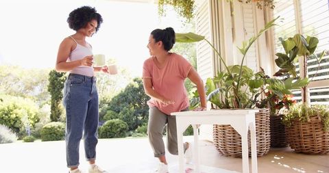 Mother and daughter sharing gardening tips on sunlit porch