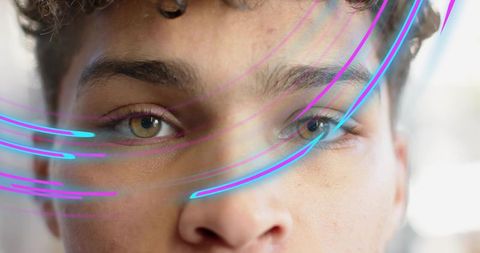 Closeup Young Man Holding Steady Gaze with Neon Light Trails Across Face Intense Portrait