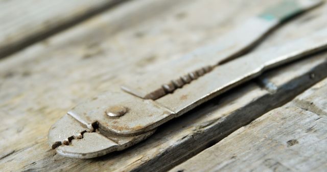 A rusty pair of pliers lies on a weathered wooden surface, suggesting a well-used tool with a history of hard work. Its worn condition speaks to the durability and longevity of such hand tools in various tasks.