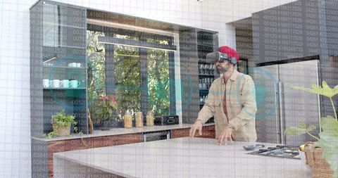 Indian man testing vr headset at modern kitchen island interacting with smart speaker