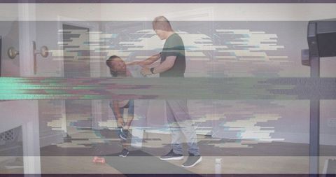 Coach assisting client with hamstring stretch on mat using resistance band for balance