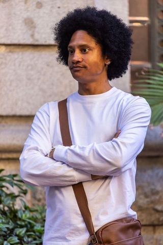 Confident african american man standing with arms crossed wearing brown crossbody bag