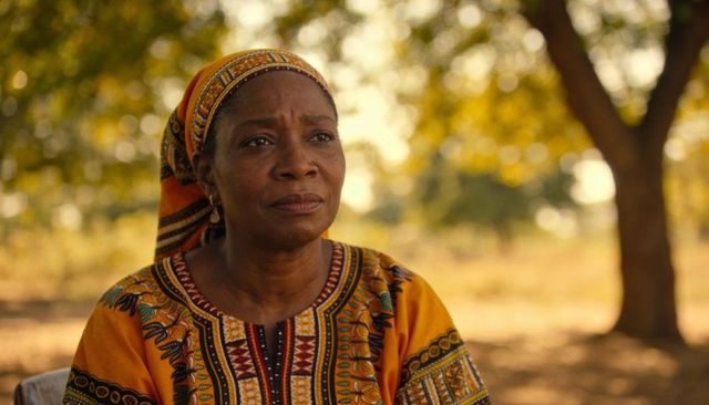 Senior woman wearing colorful patterned garment and headscarf reflecting at golden hour