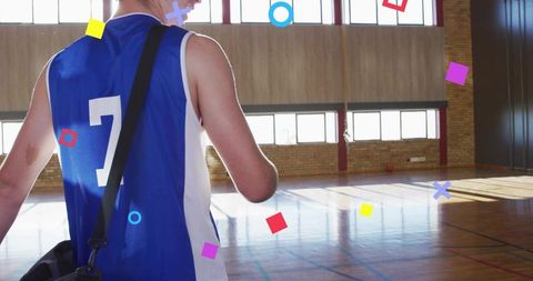Walking basketball player wearing blue number 7 jersey carrying sports bag on hardwood court