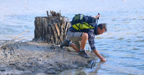 Man gathering water on riverbank for outdoor adventure