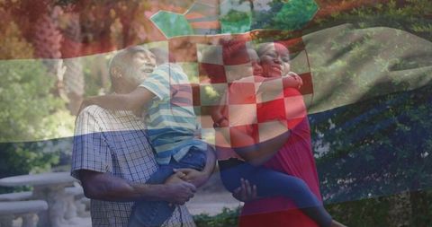 Grandfather and mother embracing children in sunlit garden with flag overlay