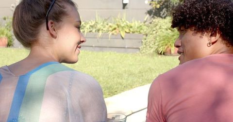Diverse couple chatting outdoors by garden border reflecting harmony
