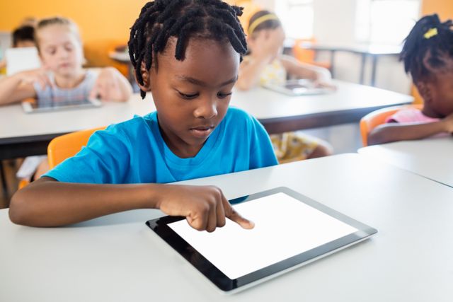 Young student using a tablet in a classroom setting, highlighting the integration of technology in education. Ideal for use in educational materials, technology in schools promotions, and articles on modern teaching methods.