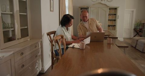 Senior Diverse Couple Planning with Laptop in Cozy Study
