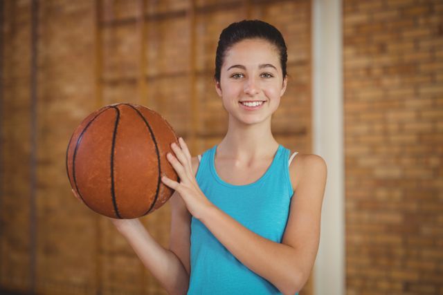 Portrait of smiling girl holding a basketball in the court