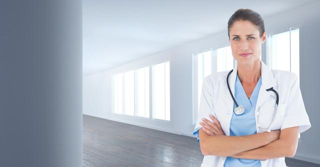 Female doctor standing confidently with arms crossed in a bright, modern hospital hallway. Ideal for healthcare, medical, and wellness content. Can be used for health care brochure, medical blog, or website promoting professional medical services.