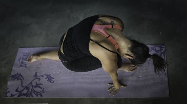 Woman performing yoga routine indoors on a purple mat. Ideal for illustrating fitness, mindfulness, and healthy lifestyle content in blogs, magazines, or social media posts promoting yoga and wellness.