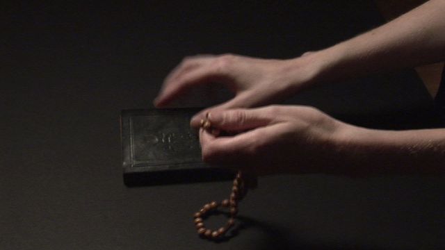 An individual holds a string of prayer beads near a dark holy book on a dark background. This video can be used to illustrate concepts of religious practice, meditation, spirituality, and devotion. It is suitable for religious blogs, articles, educational materials, and any content related to faith rituals and practices.