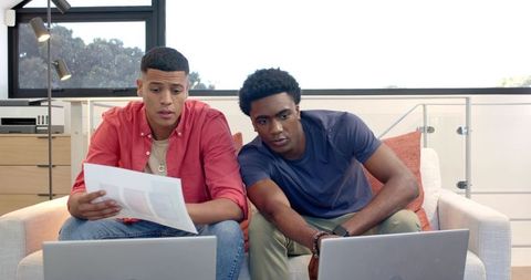 Diverse Male Colleagues Collaborating on Sofa with Laptops and Charts