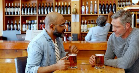 Two Friends Enjoy Conversation Over Drinks at Bar - Download Free Stock Images Pikwizard.com