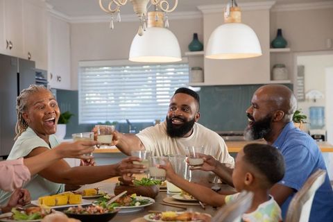 Family celebrating together by sharing meal and raising glasses