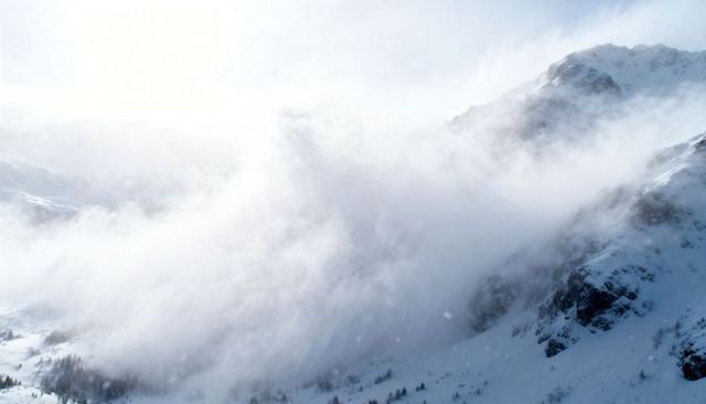 Sweeping Cloud Plume Obscuring Snowy Mountain Slopes, Sun Glare and Wind-Blown Alpine Mist