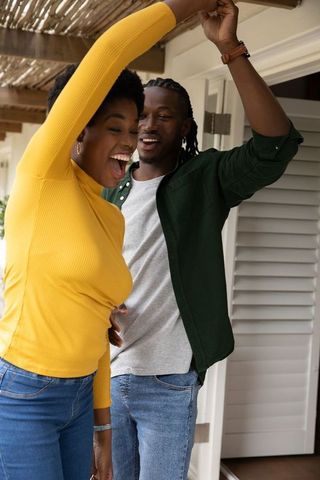 Joyful african american couple dancing on porch in daylight