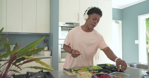 African american man preparing meal on kitchen island wearing headphones