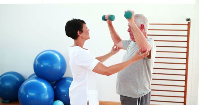 Pretty physiotherapist helping elderly patient lift hand weights at the rehabilitation center  - Download Free Stock Photos Pikwizard.com
