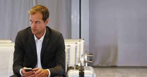 Businessman using smartphone at airport waiting area