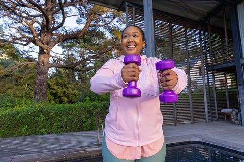 African american woman exercising with purple dumbbells outdoors