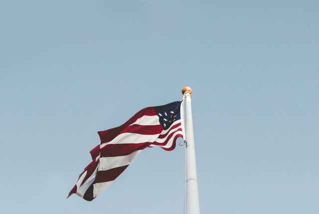This image of the American flag waving against a clear blue sky evokes a sense of patriotism and national pride. It can be used for celebrating American holidays like Independence Day or Memorial Day, enhancing websites or materials related to U.S. politics, representing American identity in presentations, or supporting educational content about the United States.