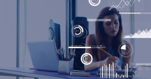 Young professional writing notes at desk with laptop and digital analytics overlays
