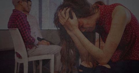 Stressed Woman Holding Head in Office with Colleagues