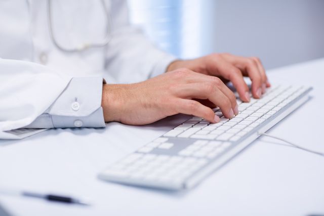Doctor typing on keyboard in clinic. Useful for illustrating medical technology, healthcare communication, and professional work environments. Ideal for medical websites, healthcare blogs, and articles about modern medical practices.