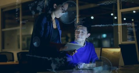 Young Professionals Collaborating on Technology Project at Night