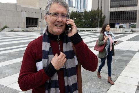Senior man talking on mobile while woman walking with coffee across urban rooftop plaza