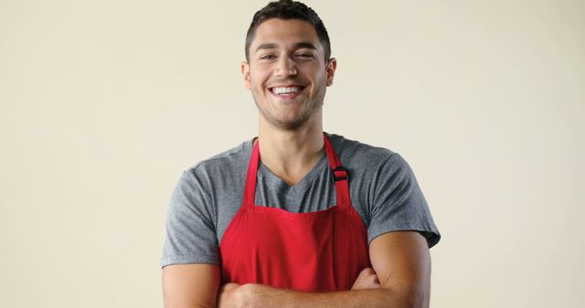 Young smiling man wearing red apron on beige background - Download Free Stock Images Pikwizard.com