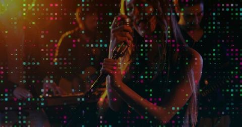 Female vocalist performing with handheld mic in moody club with colorful pixel overlay