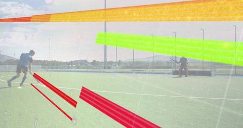 Teen field hockey player preparing strike on artificial turf with goalkeeper defending goal