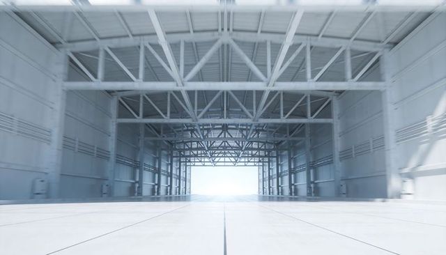 Expansive Empty Hangar Interior with Symmetrical Steel Trusses and Backlit Exit
