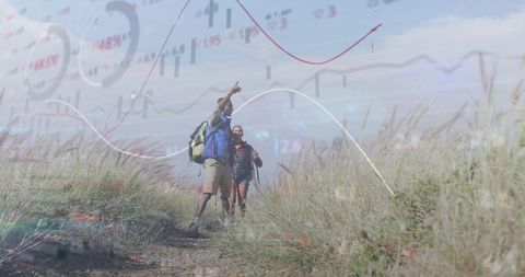 Couple hiking on coastal dunes with translucent stock market charts merging with sky