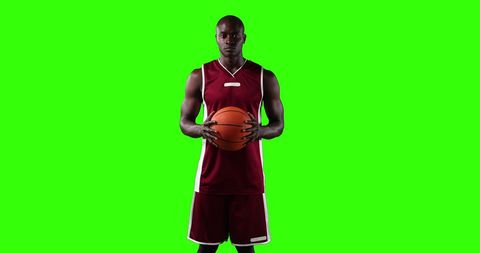 Confident Basketball Player Holding Ball Isolated on Green Background