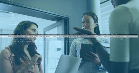 Three professional women collaborating, holding laptop and tablet, reviewing code overlay in modern 