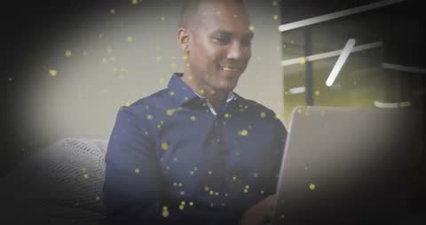 Professional Using Laptop with Golden Particles Overlay in Sleek Workspace
