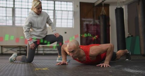 Coach guiding athlete performing push-ups with candlestick fitness data overlay in gym