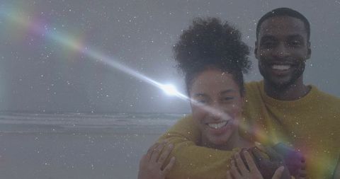 Romantic couple hugging at serene beach with lens flare