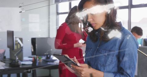 Biracial businesswoman analyzing data on tablet in office