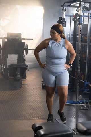 Plus-size african american woman standing in gym wearing light blue activewear