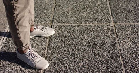 African American Man Standing on Urban Tile Pavement Wearing White Sneakers, Khaki Pants