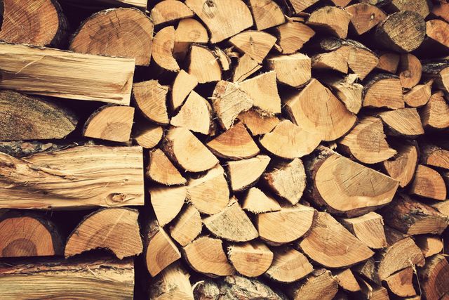 Firewood logs neatly stacked, showcasing freshly chopped wood ready for winter heating. Suitable for illustrating concepts of sustainable energy, traditional methods of heating, camping supplies, forestry resources, and rustic interior decorations.