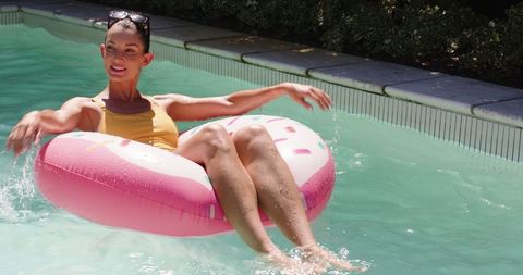 Woman enjoying relaxation on donut float in sunny pool