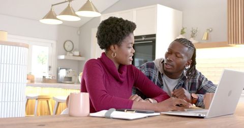 Couple Collaborating In Modern Kitchen Using Laptop