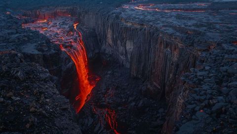 Molten lava waterfall in volcanic landscape at night