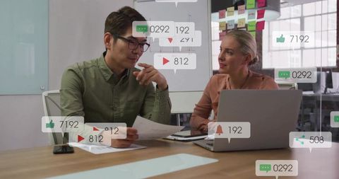 Reviewing social media analytics and documents in office, professionals collaborating